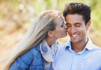 Image showing Happy couple, kiss and cheek in nature for love, bonding or support in relax for outdoor affection. Face of young woman and man smile for embrace, intimacy or romance in forest or woods together