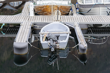 Image showing A top-down view of a single motorboat tied to a serene, empty dock, surrounded by still waters.