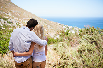 Image showing Couple, hug and love on mountains for travel, journey and holiday in nature with blue sky and ocean view. Back of romantic people on eco friendly date, hiking on hill and valentines day or tourism