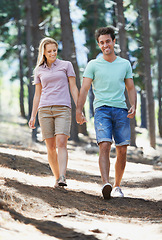 Image showing Happy couple, hiking and holding hands in forest for love, adventure or support in trust, care or bonding in nature. Young man and woman walking in romance, affection or together in outdoor woods