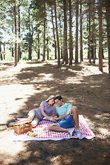 Image showing Happy couple, relax and nature for picnic, love or support in affection, date or outdoor bonding. Young woman and man sitting on floor with basket of food for embrace, eating or romance in forest