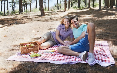 Image showing Happy couple, portrait and relax in nature for picnic, love or support in affection, date or outdoor bonding. Woman and man on floor with basket of fruit for eating or romantic dinner in forest