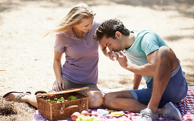 Image showing Couple, relax and eating on picnic in nature for love, care or support on outdoor date on floor mat. Man and woman with fruit basket and enjoying healthy meal, snack or vitamins together in forest