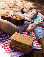 Image showing Happy couple, picnic and playing guitar for love, romance or music in outdoor bonding, fun or relaxing together in nature. Man and woman smile with instrument for acoustic sound or songs outside