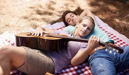 Image showing Couple, picnic and playing guitar for romance, music or love in outdoor bonding, fun or relaxing together in nature. Young man and woman smile with instrument for acoustic sound or songs outside