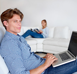 Image showing Laptop, thinking and man on sofa in home for internet, online website and social networking. Happy, couple and woman reading magazine with person on computer for relaxing, research and remote work