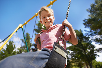 Image showing Child, swing and fun on playground in portrait, smile and outdoor adventure in childhood for recreation at park. Happy male person, active and energy on equipment, boy and play on vacation or holiday