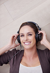 Image showing Woman, headphones for music and top view, happiness and relax at home, listening to song with technology. Podcast, radio and audio streaming, laying on floor with smile in portrait and album