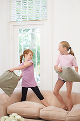 Image showing Happy kids, pillow fight and girls playing on sofa in living room together for fun bonding at home. Couch, siblings or children enjoying playful game, entertainment or weekend with cushions in lounge