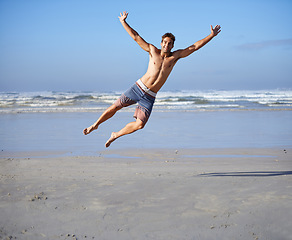 Image showing Man, jumping and portrait for happiness at beach, outdoor fun and happy in summer on vacation. Young person, playing and leisure on holiday by sea, freedom and energy for travel adventure by waves