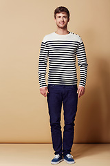 Image showing Fashion, stripe and portrait of man on beige background in trendy, stylish and casual clothes. Confident, attractive and happy person with style for positive attitude, pride and smile in studio