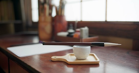 Image showing Art, paint brush and tool for in room for painter, calligraphy and drawing at a desk for creative work. Sketch paper, sumi and home studio with ink pot, table and Japanese document for creativity