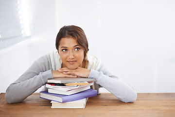 Image showing Student, happy and thinking with books by desk, idea and learning for research of assignment. Young woman, indian and positive by notebook on scholarship, studies and planning for university by table