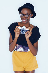 Image showing Black woman, photographer and positive in studio with camera, creativity and media for artist with creative talent. Young person, happiness and face for photoshoot, lens and focus by white background