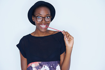 Image showing Portrait, fashion and black woman eating candy in studio on white background for sugar addiction. Food, smile and happy young african person biting confectionery for hunger or craving for sweets