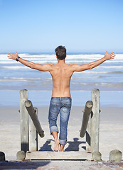 Image showing Walking, arms up and back of man at the beach on tropical vacation, adventure or holiday. Travel, stairs and confident shirtless male person on outdoor steps by ocean or sea for summer weekend trip.
