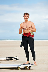 Image showing Surfer, man and face or happy with surfboard on beach with wetsuit, blue sky and confidence with sunglasses. Extreme sports, athlete and person by ocean for training, surfing workout and smile