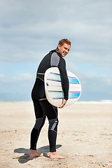 Image showing Surfer, man with surfboard and beach for fitness and extreme sports, wet suit and happy in the sun. Summer vacation with adventure and surfing in nature, ocean and exercise with hobby in Australia