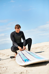 Image showing Beach, man and surfboard rope outdoor in summer for exercise, fitness and workout. Surfer, wetsuit and person with leash by ocean for safety preparation, water sports and travel on holiday by sea