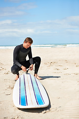 Image showing Beach, man and surfboard leash in summer for exercise, fitness and workout outdoor. Surfer, wet suit and person with rope by ocean for safety preparation, water sports and travel on holiday by sea