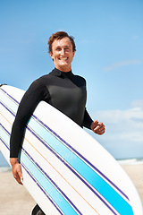 Image showing Beach, smile and man with surfboard for exercise, fitness workout or body health in summer outdoor. Surfer, wetsuit and happy person by ocean for water sports, travel or holiday vacation in Hawaii