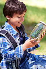 Image showing Boy, kid and smile with jar in nature, exploring and learning on adventure, hiking in park or woods for fun. Happy, young explorer and camping, discovery and glass container for collecting bugs