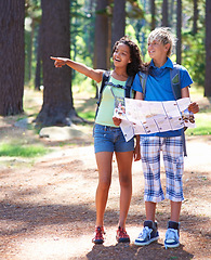 Image showing Kids, boy and girl with map and hiking in forest, backpack for adventure and point at destination in nature together. Navigation, search with youth outdoor, location for travel and trekking in woods