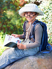 Image showing Boy, kid and hiking, book for reading and relax on rock, backpacking and adventure outdoor. Student on school field trip, nature and forest for discovery and exploration, smile in portrait and travel