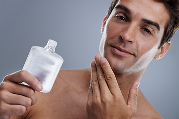 Image showing Studio, portrait and man with cologne for skincare, grooming and facial treatment or aftershave. Model, face and happy with bottle for cosmetics product, fragrance and male beauty by gray background