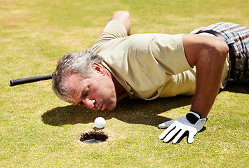 Image showing Golf, man and blowing ball into hole on a grass field for player match and putting. Fitness, sport and funny mature male person playing on a lawn to blow golfer object into target space and cheating