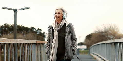 Image showing Senior woman, headphones and music outdoor, walking and wellness with audio streaming and energy. Podcast, listen to radio and sound with female person on city bridge, exercise and travel with tech