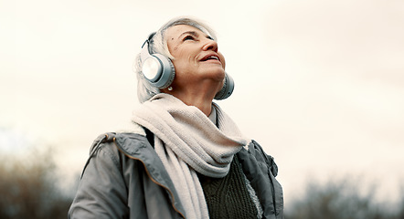 Image showing Headphones, music and senior woman in nature for wellness, mental health and happy outdoor experience. Travel, listening and streaming service or podcast of elderly person thinking in park and winter