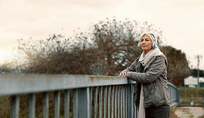 Image showing Bridge, senior woman and headphones with music and thinking outdoor with view. Elderly female person, web radio and mockup space feeling relax in retirement with audio and freedom on calm holiday