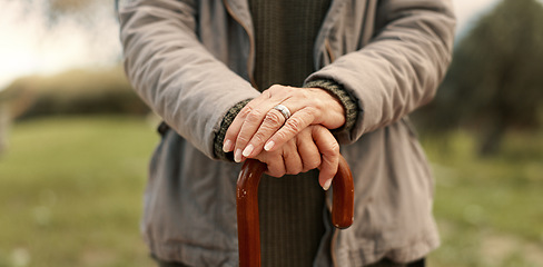 Image showing Senior cane, hands and person in nature for walking, relax and in a park for peace. Closeup, standing and an elderly woman in a garden or natural environment for wellness with a stick for support