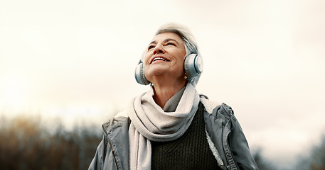 Image showing Headphones, music and senior woman in nature for wellness, mental health and happy outdoor experience. Travel, listening and streaming service or podcast of elderly person thinking in park and winter