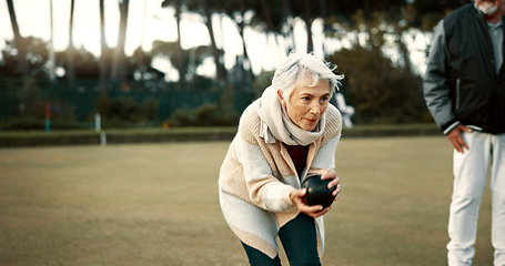 Image showing Senior woman, bowling and park on grass for sport, fitness and games for competition, health or fun. Elderly people, metal ball and lawn for contest, funny laugh or workout with blowing for good luck