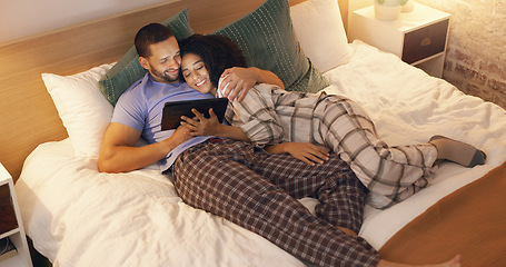 Image showing Couple, happy and hug in bedroom with tablet at night, streaming movie and relax. Smile, technology and man and woman in bed on social media app, watching online video and bonding together in home.