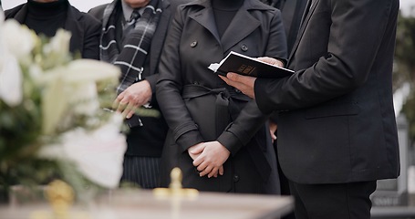 Image showing Bible, hands and family at funeral, cemetery or burial ceremony religion by coffin tomb. Holy book, death and grief of people at graveyard, Christian priest reading spiritual gospel and faith in God