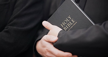 Image showing Bible, funeral and hands closeup of a priest for religion, sad and mourning event in church. Faith, male person and spiritual passage with worship and book for grief with support and condolences