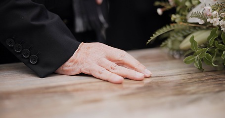 Image showing Death, funeral and hand on coffin in mourning, family at service in graveyard or church for respect. Flowers, loss and people at wood casket in cemetery with memory, grief and sadness at grave burial