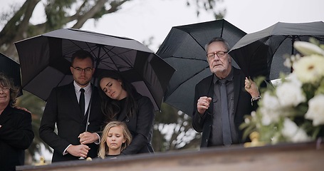 Image showing Death, funeral and umbrella, people at coffin for service in graveyard in respect, mourning and support. Flowers, rain and loss, family at casket in cemetery with memory, grief and grave for burial.