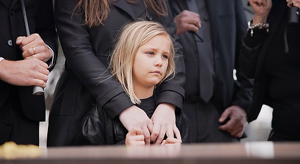 Image showing Child, sad and family at funeral at graveyard ceremony outdoor at burial place. Death, grief and group of people with casket or coffin at cemetery for service while mourning a loss at event or grave