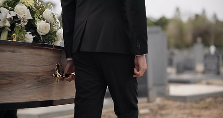 Image showing Coffin, hands and man walking at funeral ceremony outdoor with pallbearers at tomb. Death, grief and person carrying casket at cemetery, graveyard or family service of people mourning at windy event