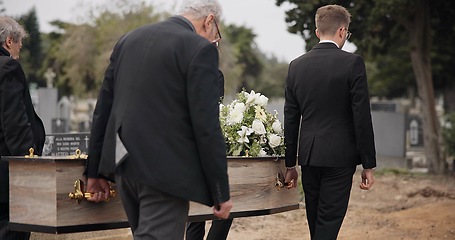 Image showing Coffin, men and pallbearers walking at graveyard ceremony outdoor at burial tomb. Death, grief and group casket at cemetery, carrying to funeral and family service of people mourning at windy event