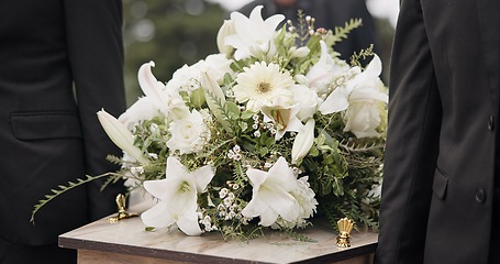 Image showing Carrying coffin, flowers and people at funeral for service, mourning and at the graveyard. Closeup, support and group of family or friends with respect while holding casket during a ceremony together