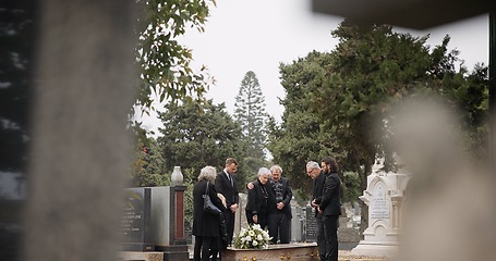 Image showing People at a funeral, death and graveyard with family mourning outdoor, grief and loss with coffin. Cemetery, ceremony and sad, goodbye and burial service with support, comfort and empathy at memorial