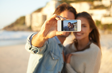 Image showing Couple, selfie and smile for phone screen by ocean for memory on vacation with care, love and tropical beach. Man, woman and hug with photography, profile picture or mobile app by sea on social media