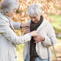 Image showing Senior friends, care and support by outdoor in nature, together and bonding on retirement on holiday. Elderly women, help and tie button on vacation in countryside, love and happy in park in winter