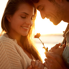 Image showing Flower, smile and young couple at beach on vacation, adventure or holiday for valentines day. Love, sunset and man and woman with floral plant by ocean for tropical weekend trip on romantic date.