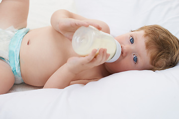 Image showing Portrait, bottle and baby in bed drinking milk for meal, feeding or food lying down in home. Hungry child, wellness and healthy boy toddler with formula for nutrition, natural diet or growth alone